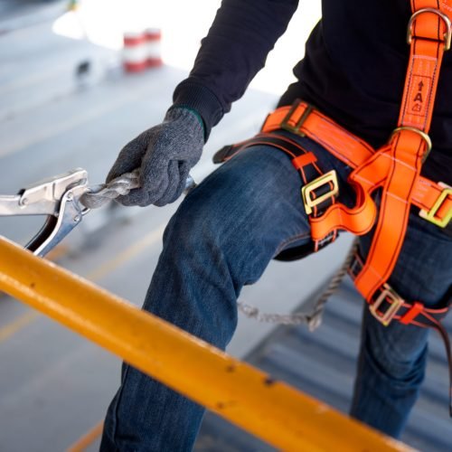 Construction worker use safety harness and safety line working on a new construction site project.